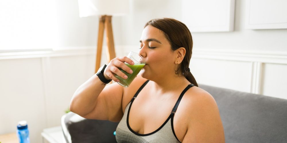 Frau trinkt auf dem Sofa einen grünen Smoothie